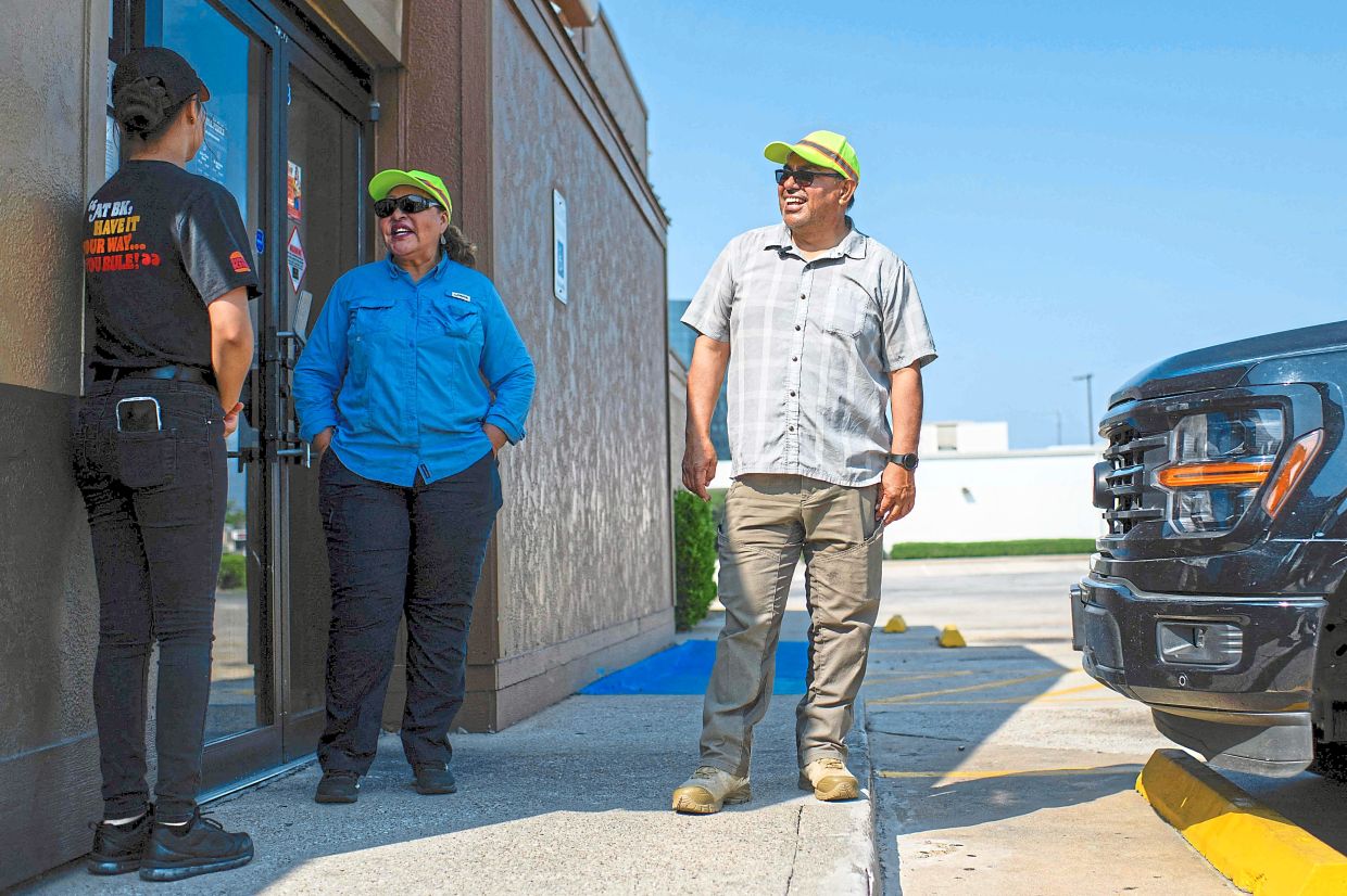 Grifaldo (centre) and Mendoza speaking to a migrant in front of a store in Houston, Texas.— AFP