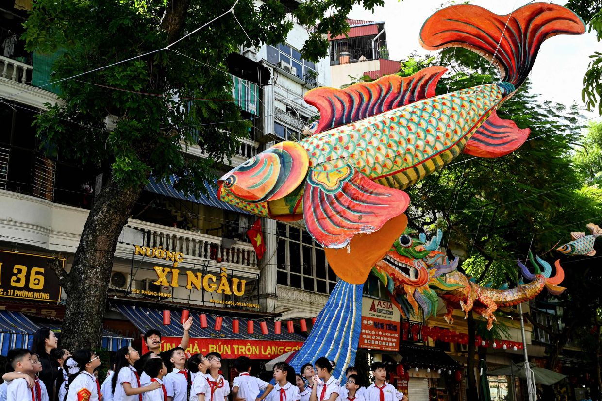 Primary school students listen to an introduction about street lanterns in Hanoi's Old Quarter. -- Photo by Nhac NGUYEN / AFP