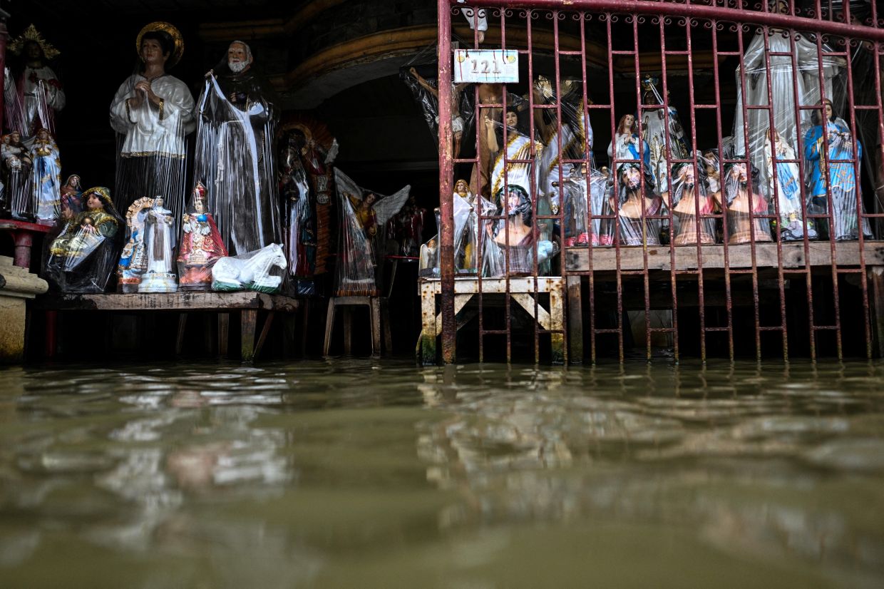 Religious statues made of resin are displayed at a flooded shop, intensified by rain caused by Severe Tropical Storm Matmo, in San Roque, Macabebe, Pampanga, Philippines, on Saturday, October 4, 2025. -- Photo: REUTERS/Noel Celis