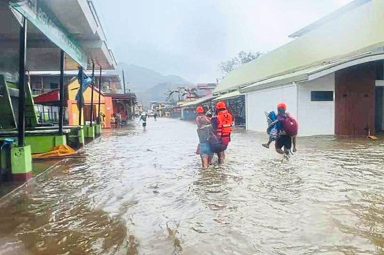 Water evac: The Philippine Coast Guard and rescuers evacuating residents along flooded streets due to Tropical Storm Bualoi in San Agustin. — AP