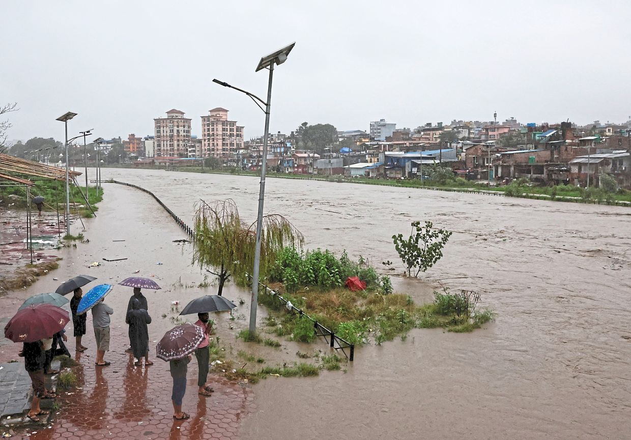 People looking towards the overflowing Bagmati River spurred by the downpour. — Reuters 