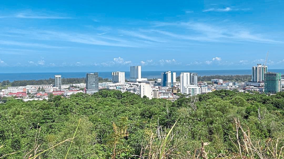 A panoramic view of Miri, where modern skyscrapers rise above the rainforest canopy, looking out to the South China Sea.