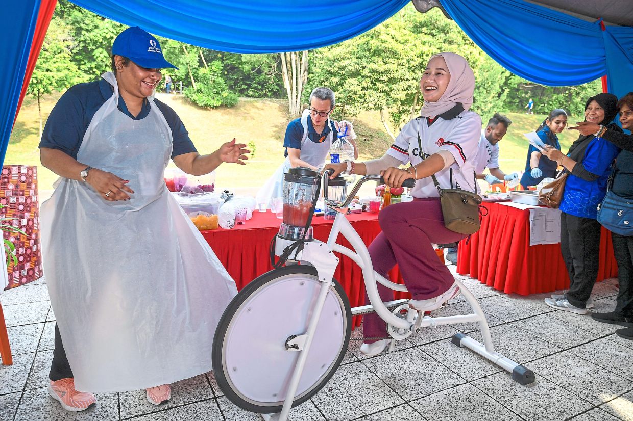 A participant happily pushing the pedals of a blender bike to make fruit juice. 