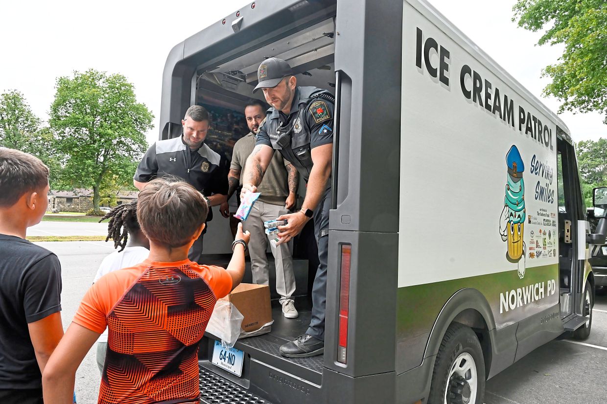 Children finishing a summer camp activity in Norwich queue for ice cream.