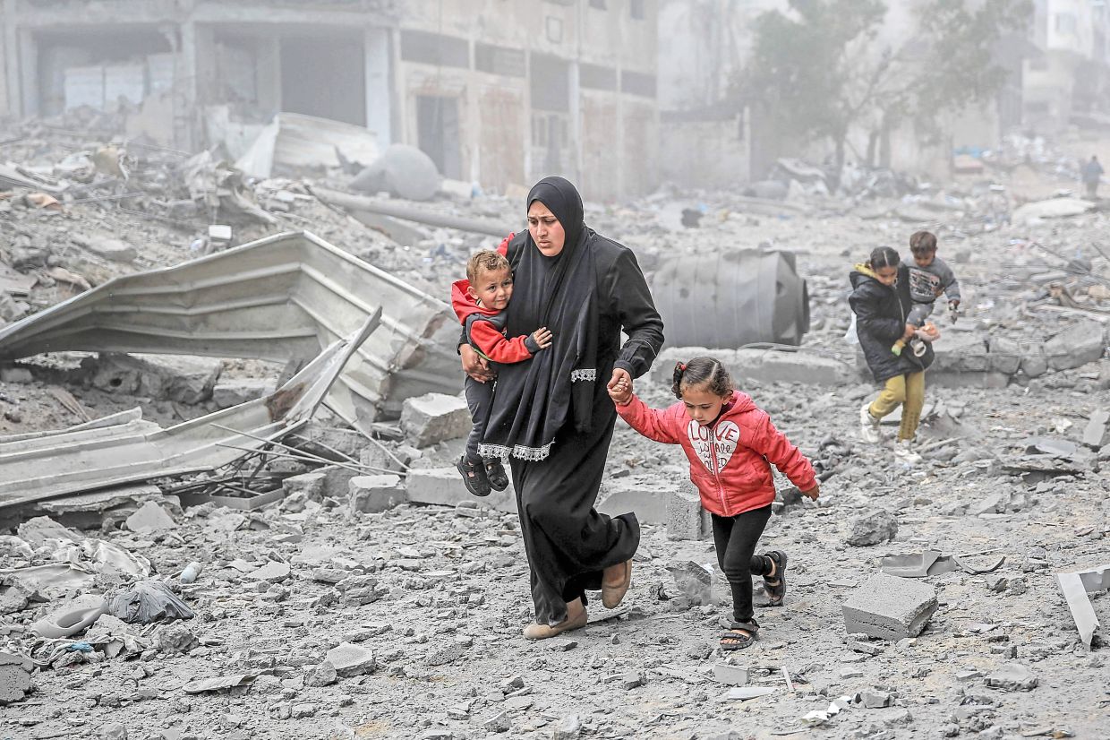 Palestinians flee the area after Israeli bombardment in central Gaza City on March 18, 2024. — AFP
