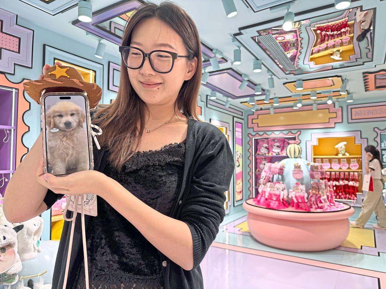 Zheng choosing for her dog a mini cowboy hat at Miniso Land, Guangzhou.