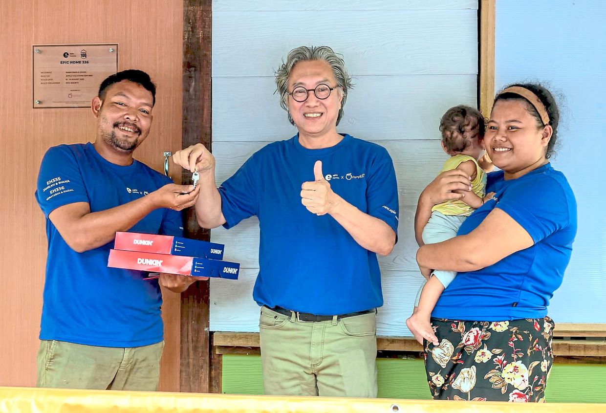 Koh handing over the keys to a recipient of a completed home.