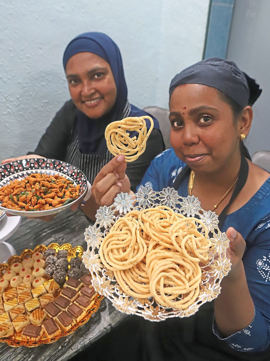 Sha Nanthini (right) and her sister-in-law Fairuza Abdul Rahman showing a mix of biscuits and snacks for Deepavali at her home in Desa Mawar in Bandar Baru Air Itam, Penang.