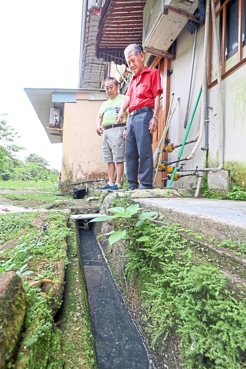 Taman Ungku Tun Aminah Flats Block 62 MC chairman Hi Kon Jin (right) and Chan showing a clogged drain at one of the blocks. — Photos: THOMAS YONG/The Star
