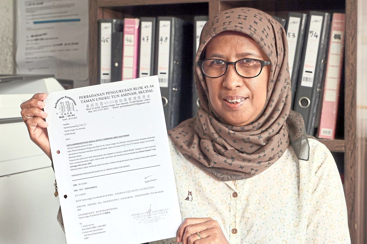 Norashikin with a notice issued by the management to residents instructing them to stop all illegal renovation activities.