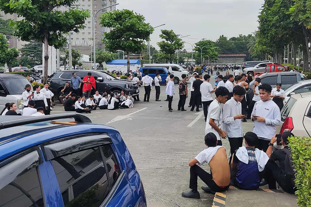 Employees at a shopping mall gather outside the building in Davao City Oct 10 after the 7.6-magnitude earthquake. - AFP