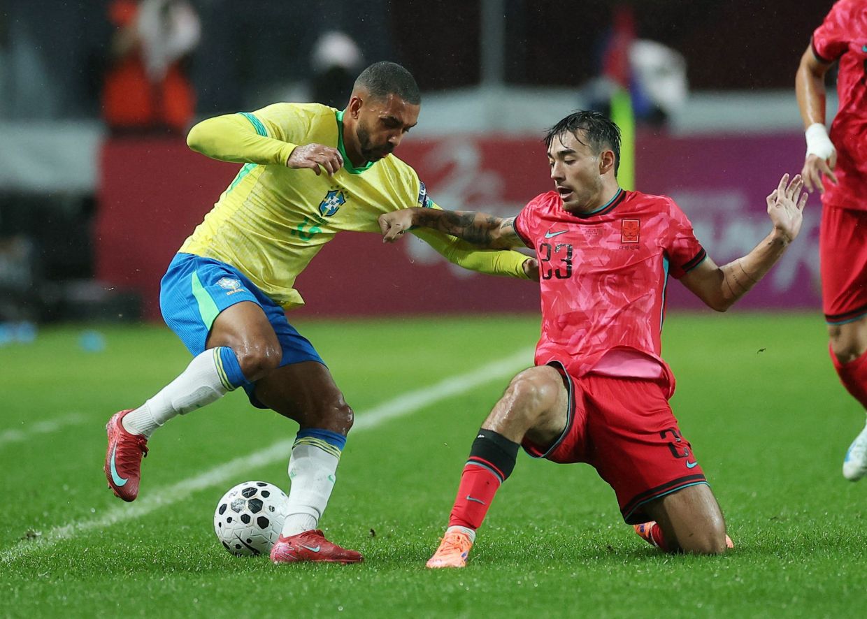 Soccer Football - International Friendly - South Korea v Brazil - Seoul World Cup Stadium, Seoul, South Korea - October 10, 2025. Brazil's Paulo Henrique in action with South Korea's Jens Castrop. Brazil won 5-0. -- Photo: REUTERS/Kim Hong-Ji