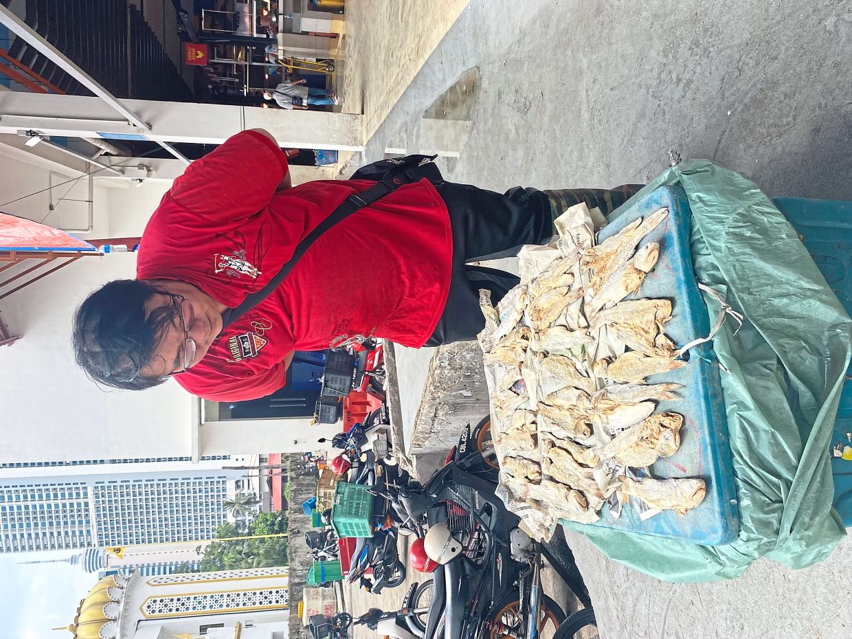 Chew checking unsold threadfin fish that is being preserved with salt to prevent spoilage.