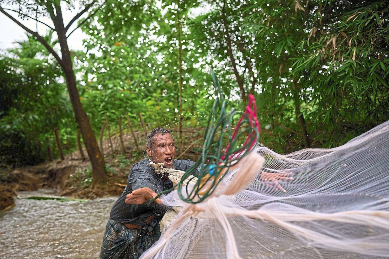 Lifeline: Mahmud throwing a fishing net into the river near the Mae La refugee camp. — AP