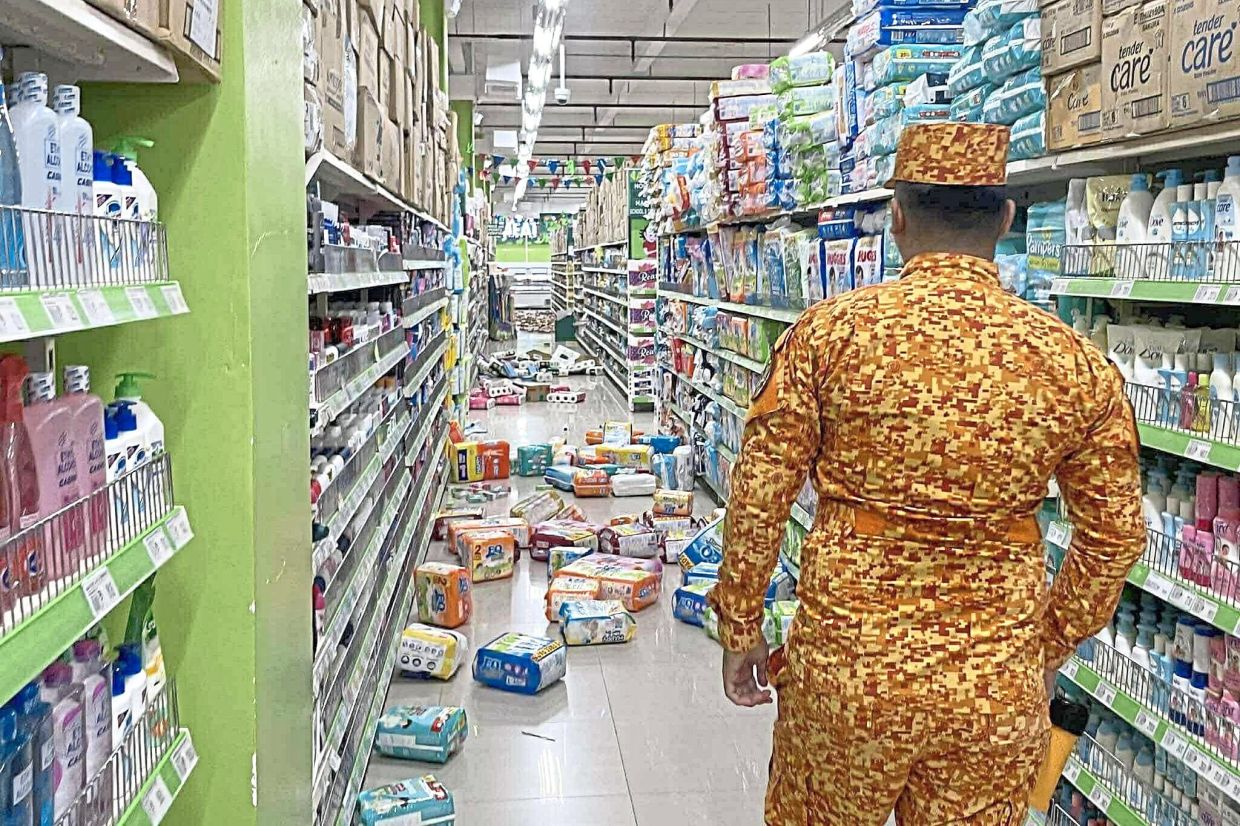 Off the shelves: A fireman looking at items scattered on the floor in a supermarket in Banaybanay, southern Philippines. — AP