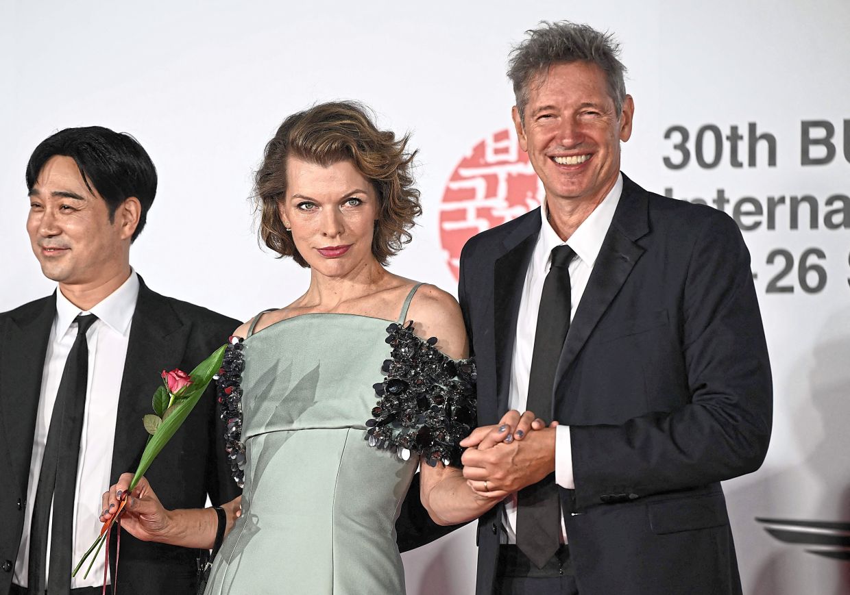 Action star Jovovich and her husband Paul Anderson (right) arrive on the red carpet during the opening ceremony of the 30th Busan International Film Festival (BIFF) at the Busan Cinema Center in Busan. — AFP