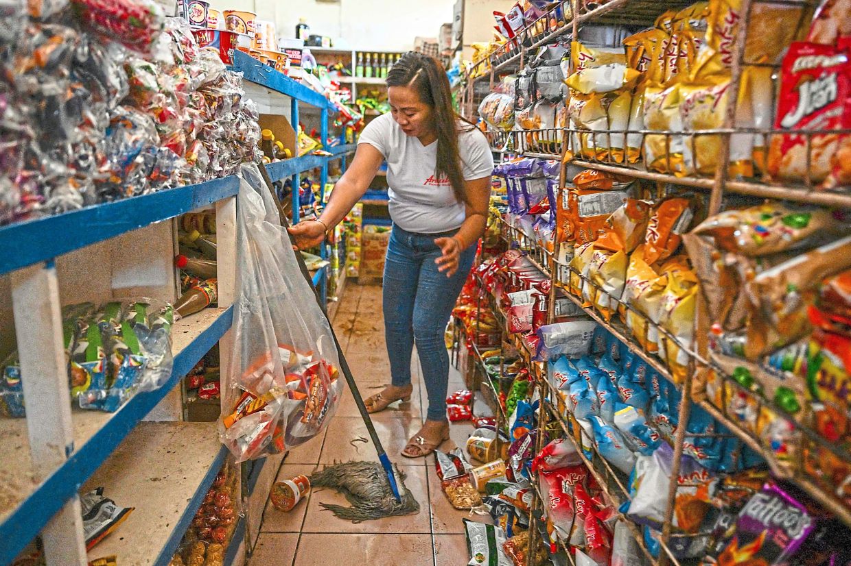 Filipinos cleaning up their shops inearthquake-wracked Manay. — AFP