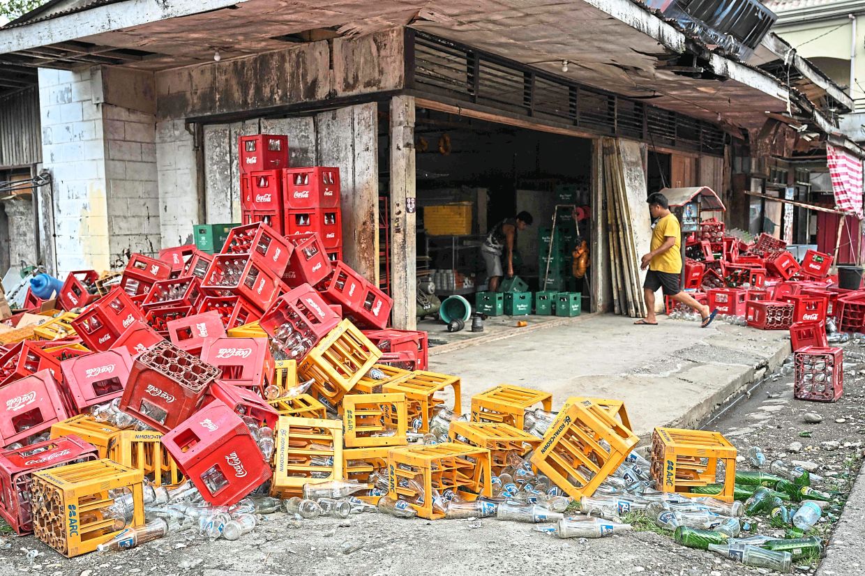 Daunting task: Filipinos cleaning up their shops inearthquake-wracked Manay. — AFP