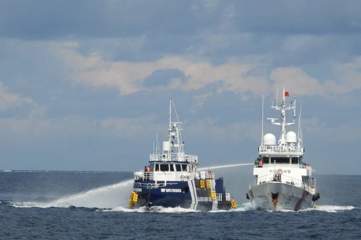 In this photo provided by the Philippine Coast Guard, a Chinese Coast Guard vessel, right, fires its water cannon at the Philippines' BRP Datu Pagbuaya near Philippine-occupied Thitu island, locally called Pag-asa island, at the South China Sea on Sunday, Oct. 12, 2025. -- Philippine Coast Guard via AP