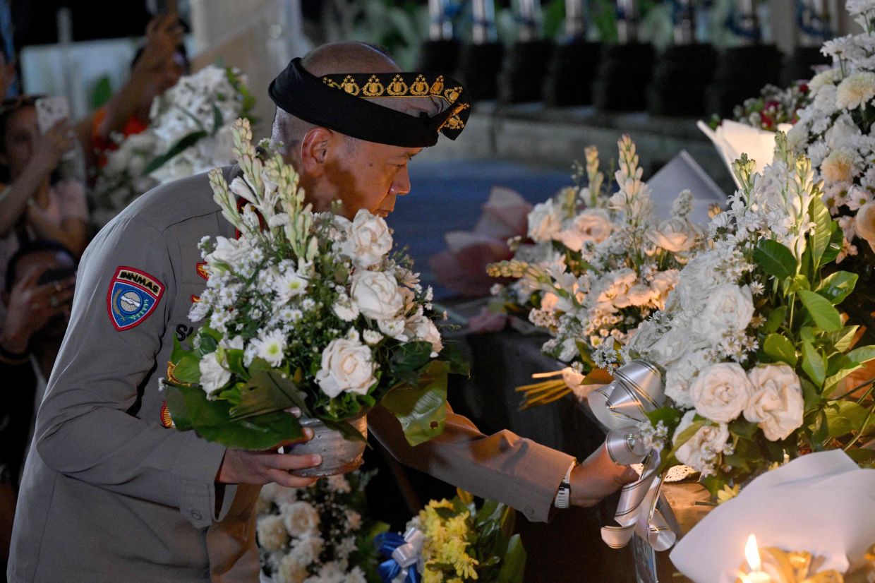 A policeman places flowers at the memorial for those who lost their lives in the 2002 Bali bombings on the 23rd anniversary of the attacks in Kuta, near Denpasar, on Indonesia's Bali island on Sunday, October 12, 2025. -- Photo by SONNY TUMBELAKA / AFP