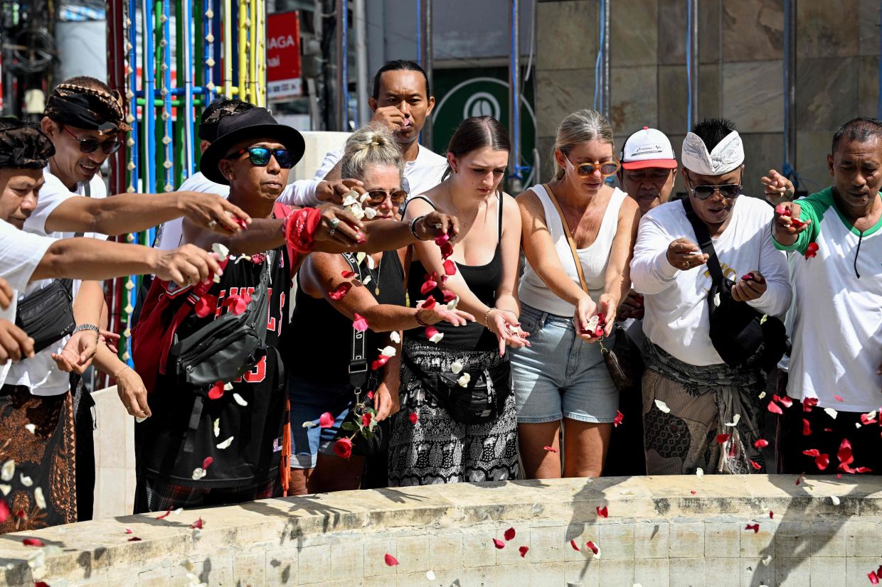 People throw flower petals at the memorial for those who lost their lives in the 2002 Bali bombings on the 23rd anniversary of the attacks in Kuta, near Denpasar, on Indonesia's Bali island on Sunday, October 12, 2025. -- Photo by SONNY TUMBELAKA / AFP