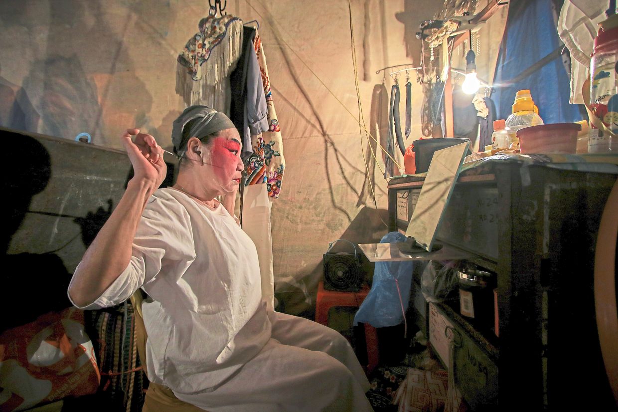 Putting on thick face paint and all ready in full costume for the performance on stage.