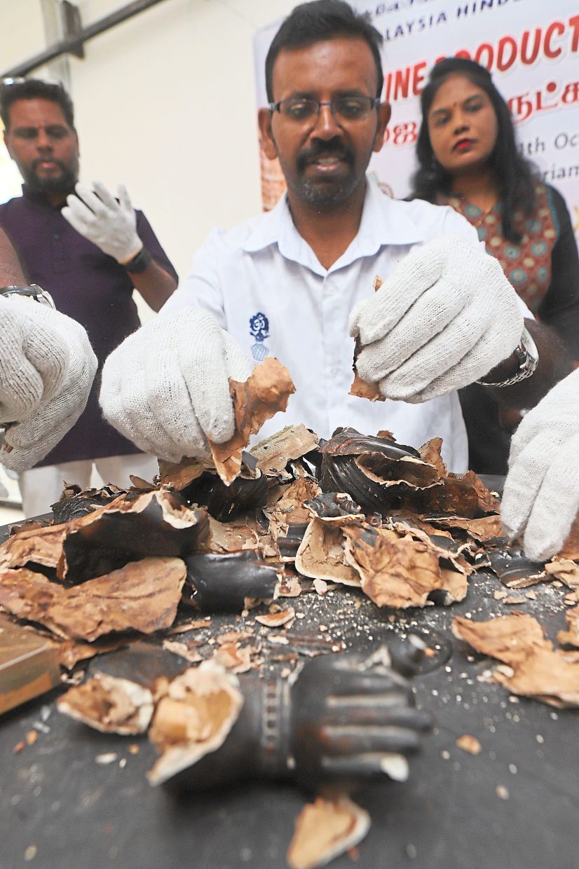 Eco drive: MHS Penang State Welfare chairman B. Senthilkumar crushing a damaged idol of Lord Ganesha into smaller pieces before being disposed of. — LIM BENG TATT/The Star