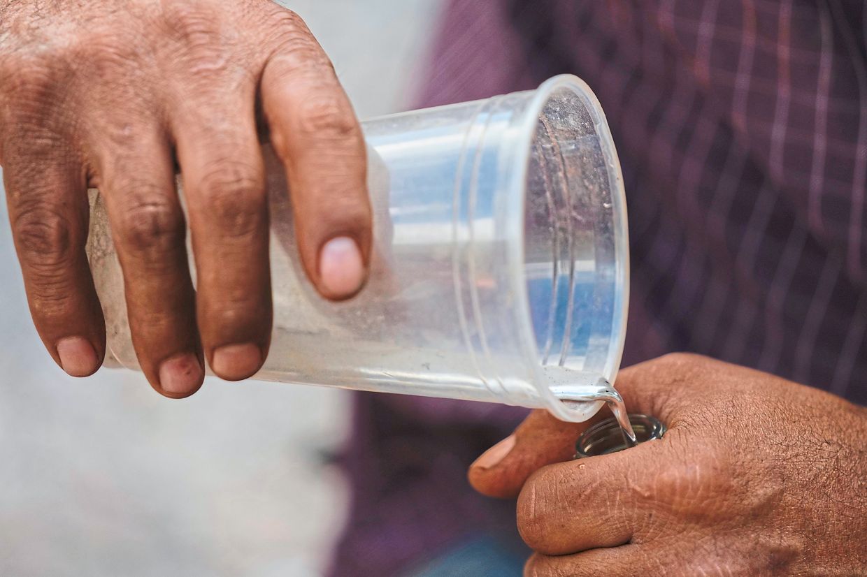 A miner transfers a sample of mercury into a bottle.