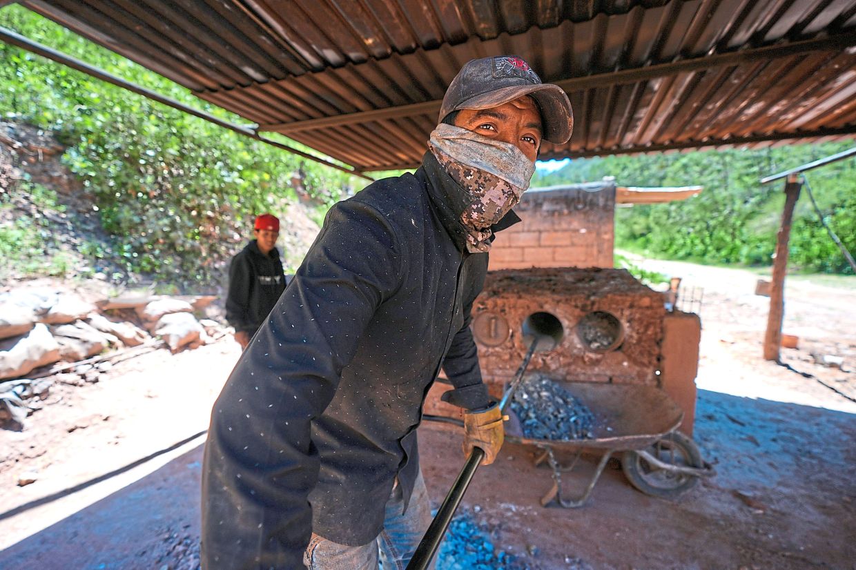 Martinez removes mercury rocks from furnace tubes after baking them.