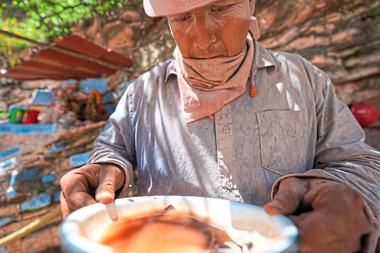 Flores analyses a sample of sand and rocks to determine the amount of mercury ore before cooking it.