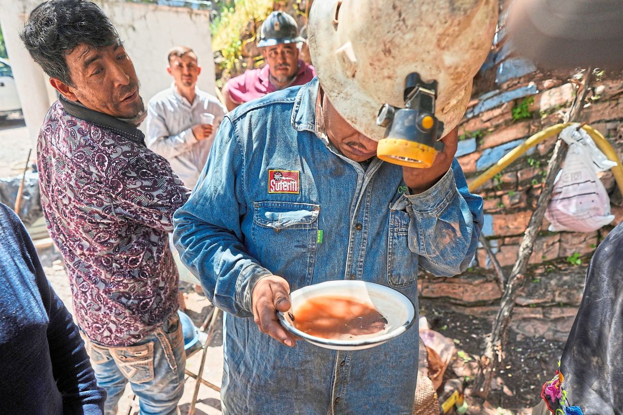 A miner analyses a sample of sand and rocks to determine the amount of mercury ore.