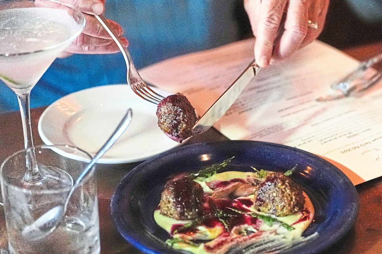 Lebanese lamb meatball, which includeds locally foraged ingredients, is selected by a patron during dinner service.