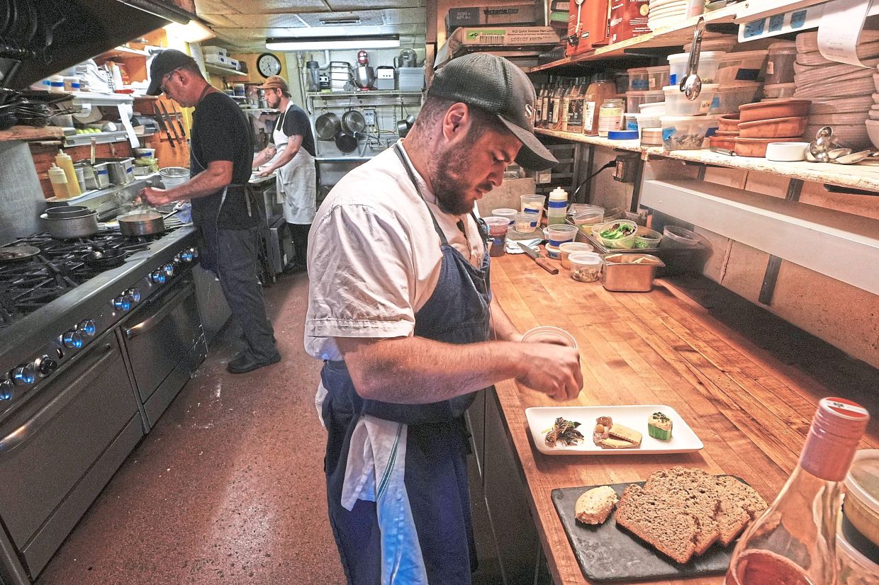 Chef Jake Vatalaro sprinkles locally foraged locust flower seasoning on a Chef's Meze Plate, which includes locally foraged mushrooms.
