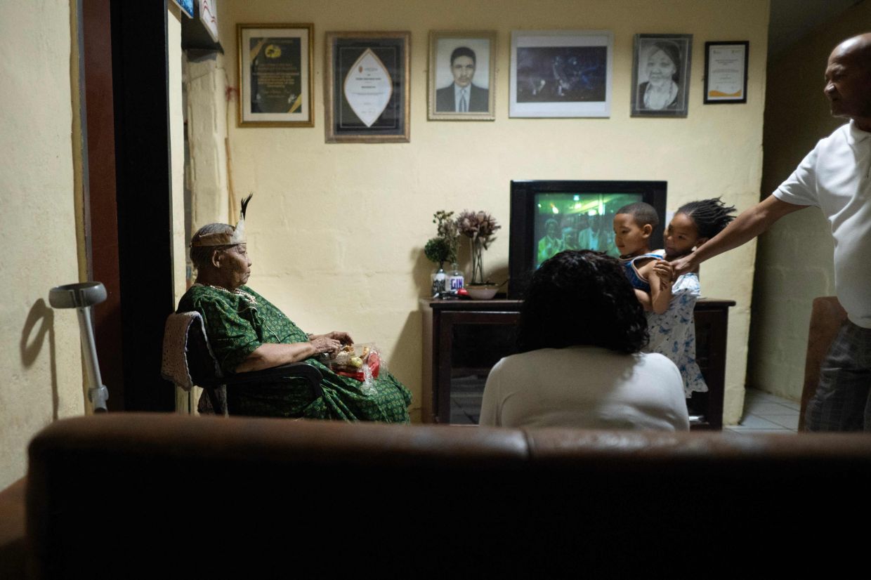Esau (left), one of the last people to speak N|uu, watches television with members of her family, in her home. Photo: AFP 