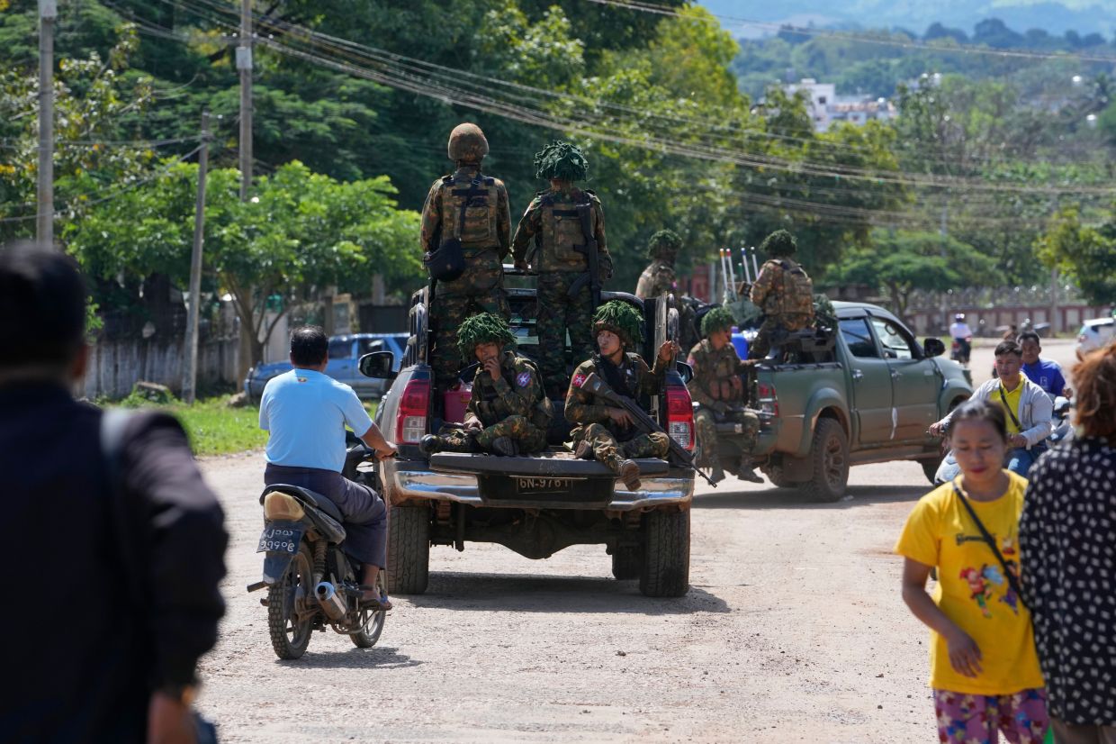 In this photo taken during a trip organised by pro-military Myanmar media, soldiers patrol a road in Kyaukme, northern Shan State, Myanmar, Friday, Oct. 10, 2025. -- AP Photo/Aung Shine Oo