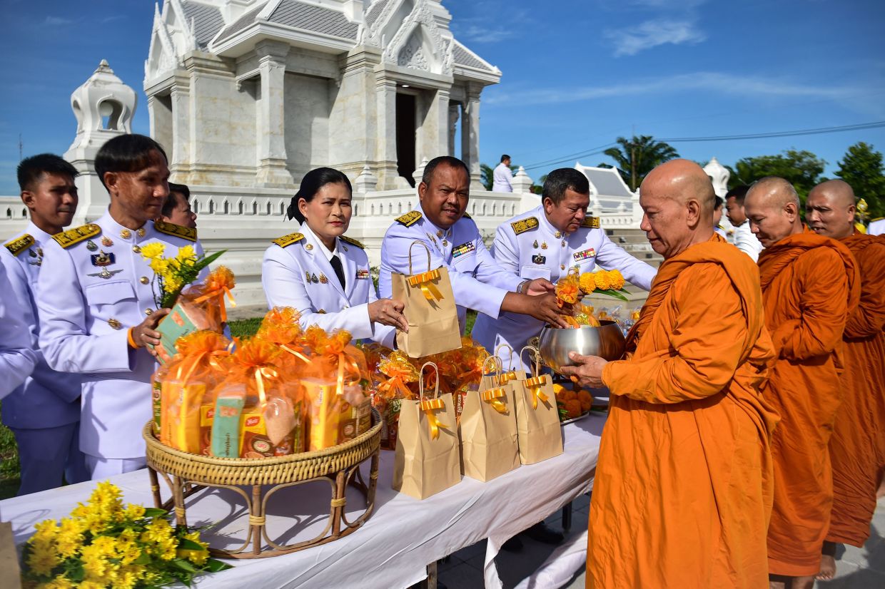 Buddhist monks receive alms from civil servants during an event commemorating the death anniversary of Thailand's late king Bhumibol Adulyadej at the city hall in the southern province of Narathiwat on Monday, October 13, 2025. -- Photo by Madaree TOHLALA / AFP