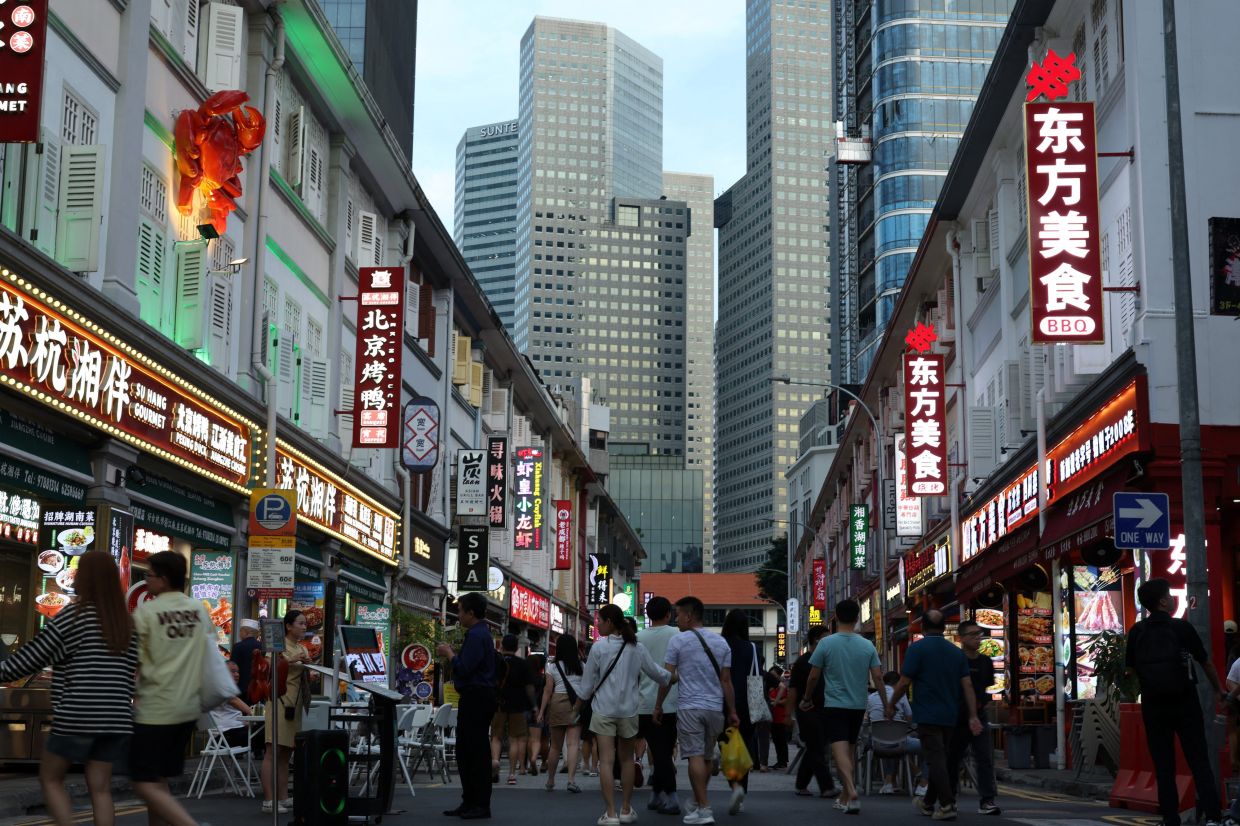 People pass restaurants selling Chinese cuisine at Liang Seah Street in central Singapore. -- REUTERS/Edgar Su