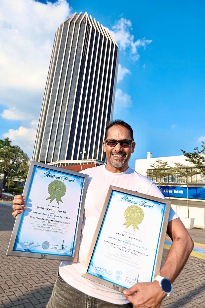 Ravinder showing some of the national records MTA has earned this year. Behind him is Menara MBPJ in Petaling Jaya where the tower run will take place.