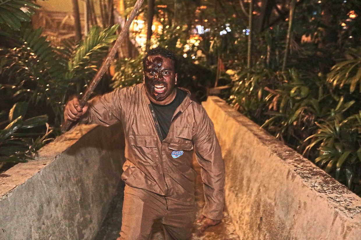 A masked figure with a weapon stalks the narrow paths of Sunway Lagoon during Nights of Fright 11. — YAP CHEE HONG / THE STAR