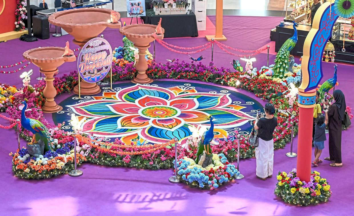 Shoppers taking photos of the colourful Deepavali set-up at The Curve. The grand pink lotus installation at Suria KLCC, symbolising renewal and hope. — Photos: IZZRAFIQ ALIAS/The Star