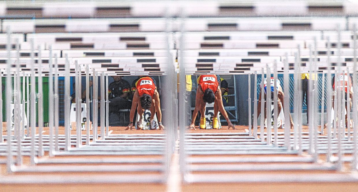 Athletes getting set on the starting line for the hurdles race.