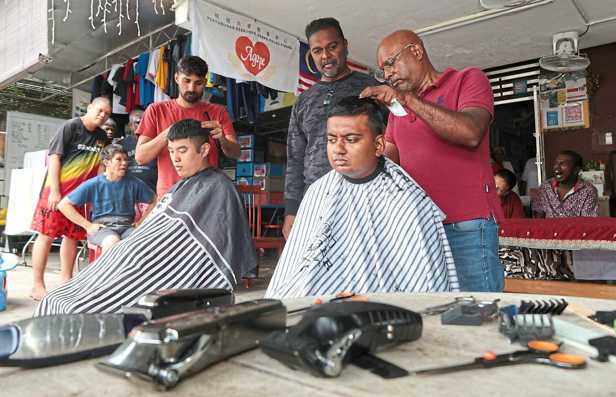 Vimalan (centre) looking on as barbers give residents of Agape Home in Island Glades a free haircut in conjunction with Deepavali.