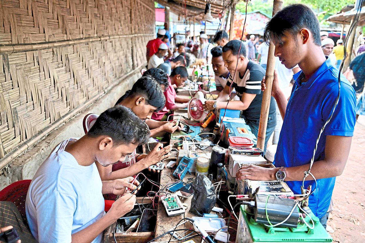 Handy men: Rohingya refugees repairing their cell phones in a service centre at Balukhali camp in Ukhia. — AFP