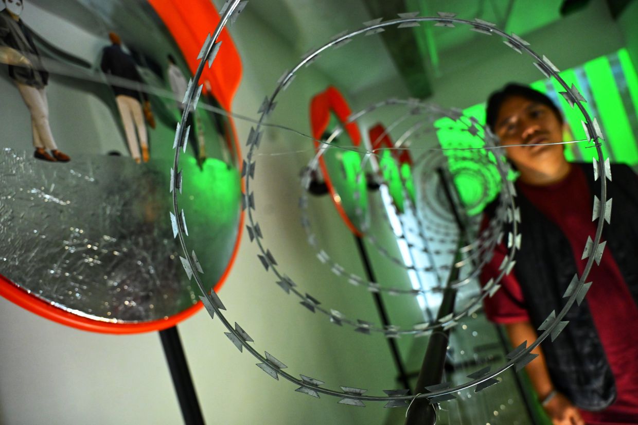 'I’m drawn to anonymity – to how ambiguous figures hide their true nature and intent,” says Zulkefli Jais, pictured with his installation 'Watchtower' at Galeri Sasha in Kuala Lumpur. Photo: The Star/Raja Faisal Hishan
