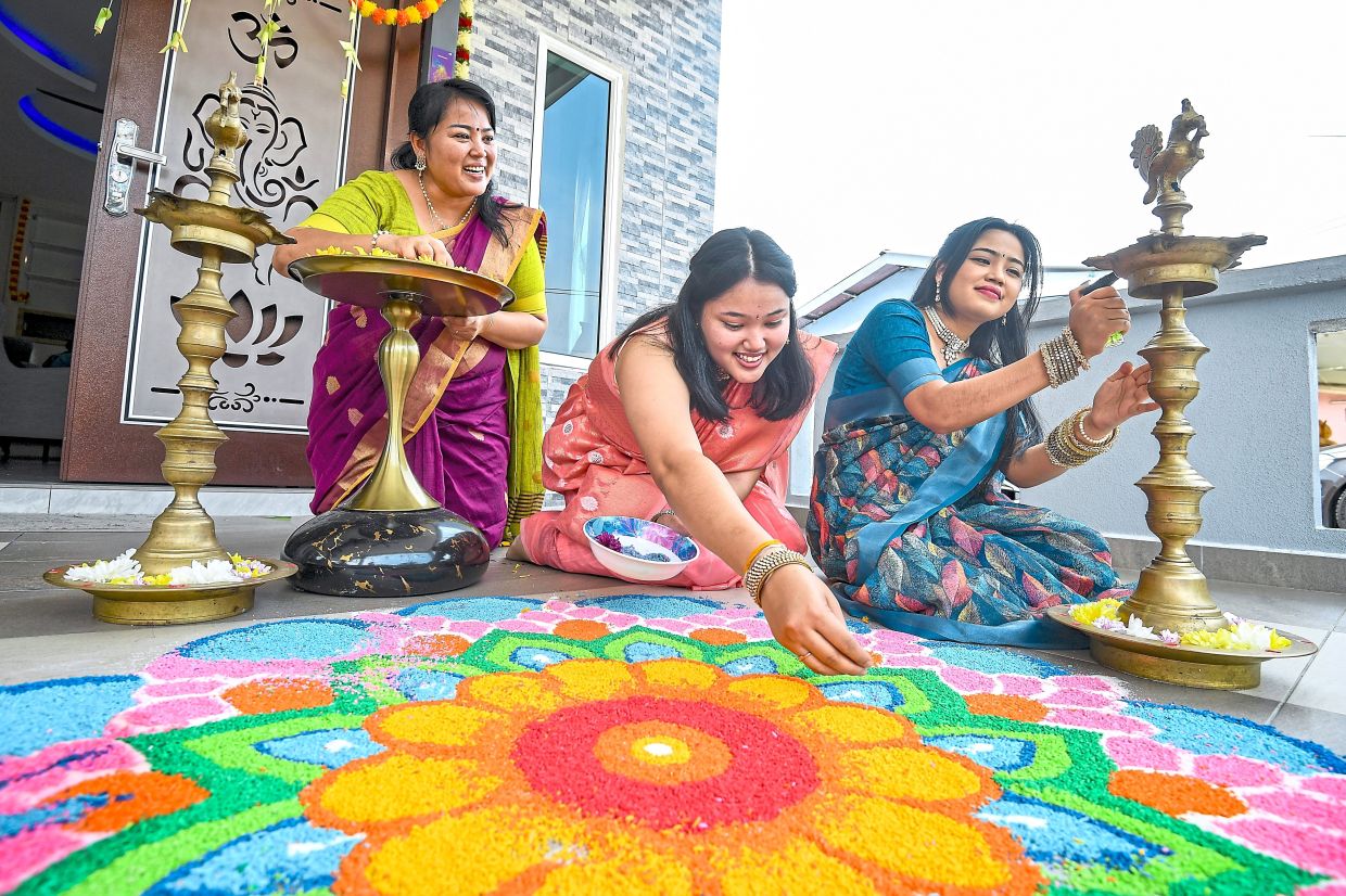 From left: Kalarani, Yashinavi and Mishalini add the finishing touches to a colourful kolam to welcome Deepavali. 