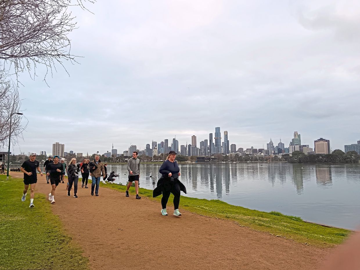 Runners at Albert parkrun in Melbourne, Australia, with the course winding around the lake.