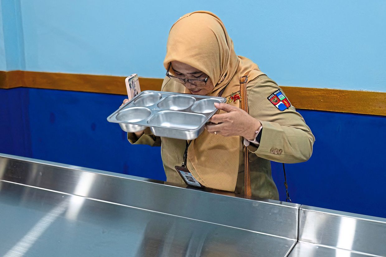A Health Department staff member checking a tray used to serve food to students, at a nutrition service unit in Bogor, West Java. — AFP