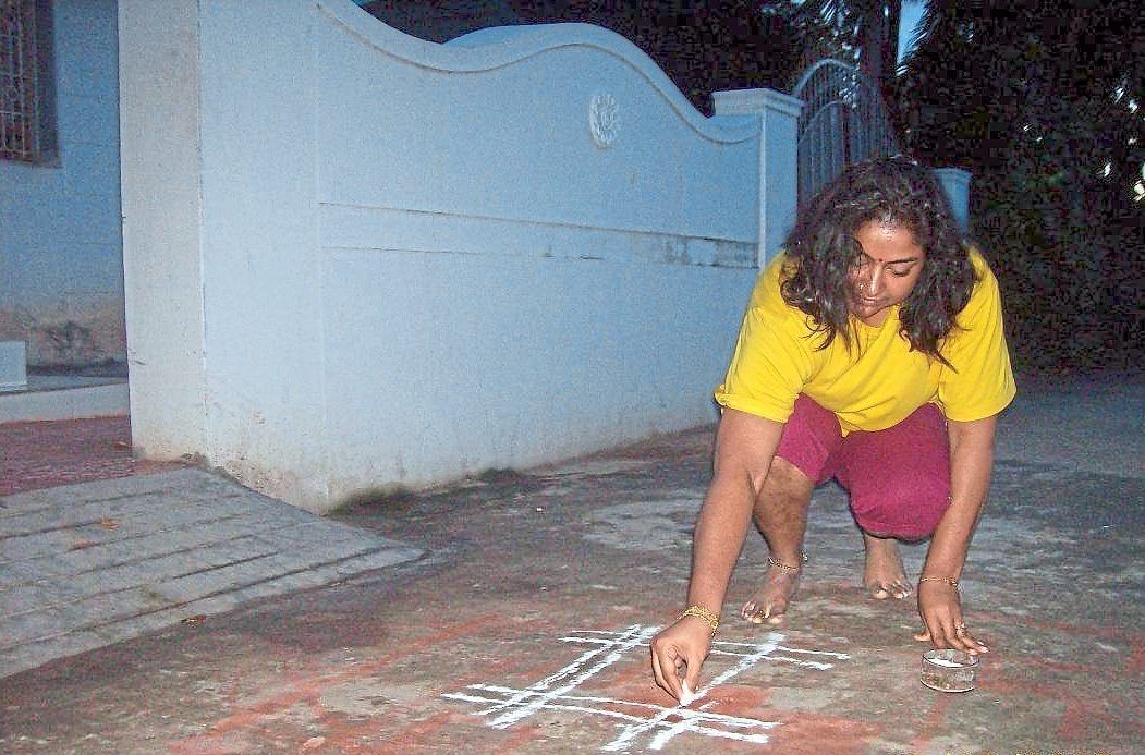 Saraswathy creating a kolam outside a family friend’s house in Tamil Nadu, India, during a previous Deepavali visit.