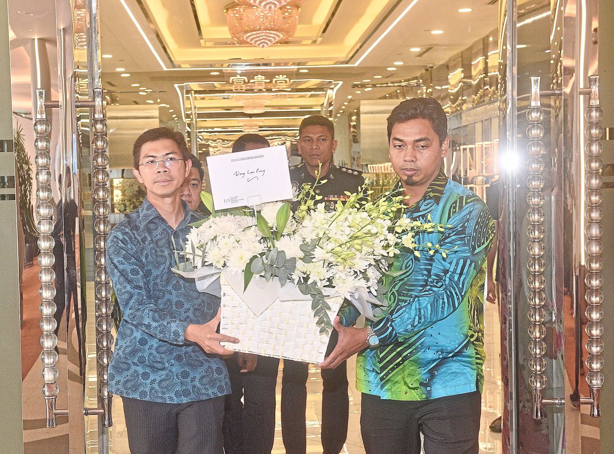 Heartfelt condolences: Representatives from Istana Negara carrying a bouquet of flowers into the memorial hall where (pic, below) Shing Xuen’s remains rest. — Low Lay Phon/The Star