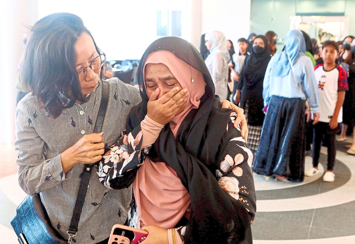 Unbearable grief: A tearful teacher being comforted by her colleague at the wake as other teachers and students look on.